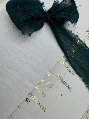 Eleganckie zaproszenie ślubne ze złotym napisem i kopertą na tle dekoracyjnym