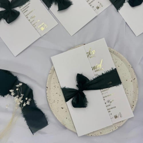 Zbliżenie na złoty napis na folderowym zaproszeniu ślubnym glamour