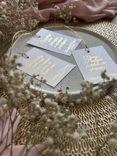 Detal zawieszki na butelkę weselną z personalizacją, złotym sznureczkiem i różowym papierem