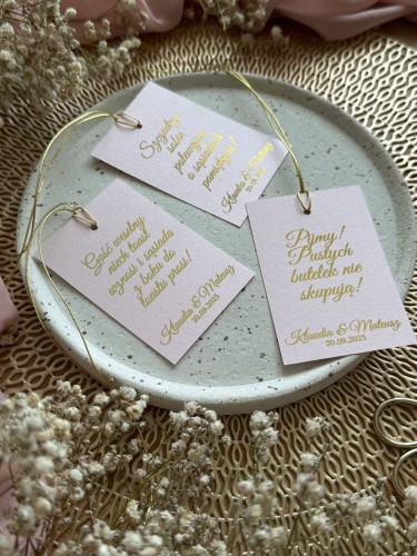 Zawieszki na alkohol weselny z papieru różowego ze złotym sznureczkiem – widok kilku sztuk