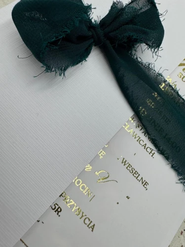 Eleganckie zaproszenie ślubne ze złotym napisem i kopertą na tle dekoracyjnym