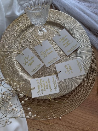 Elegancka zawieszka weselna na alkohol – złocona nazwa i ozdobny papier perłowy w aranżacji stołowej